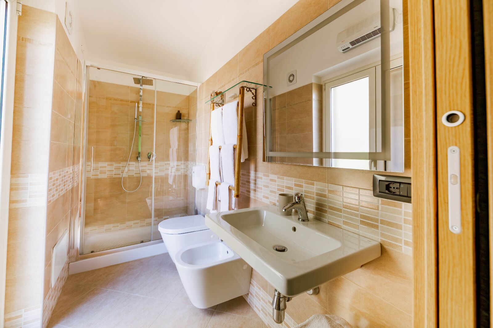 Une salle de bain équipée d’une douche, de toilettes, d’un lavabo et d’un grand miroir.
