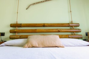 Un lit avec une tête de lit en bois, un seul oreiller beige et un mur uni.