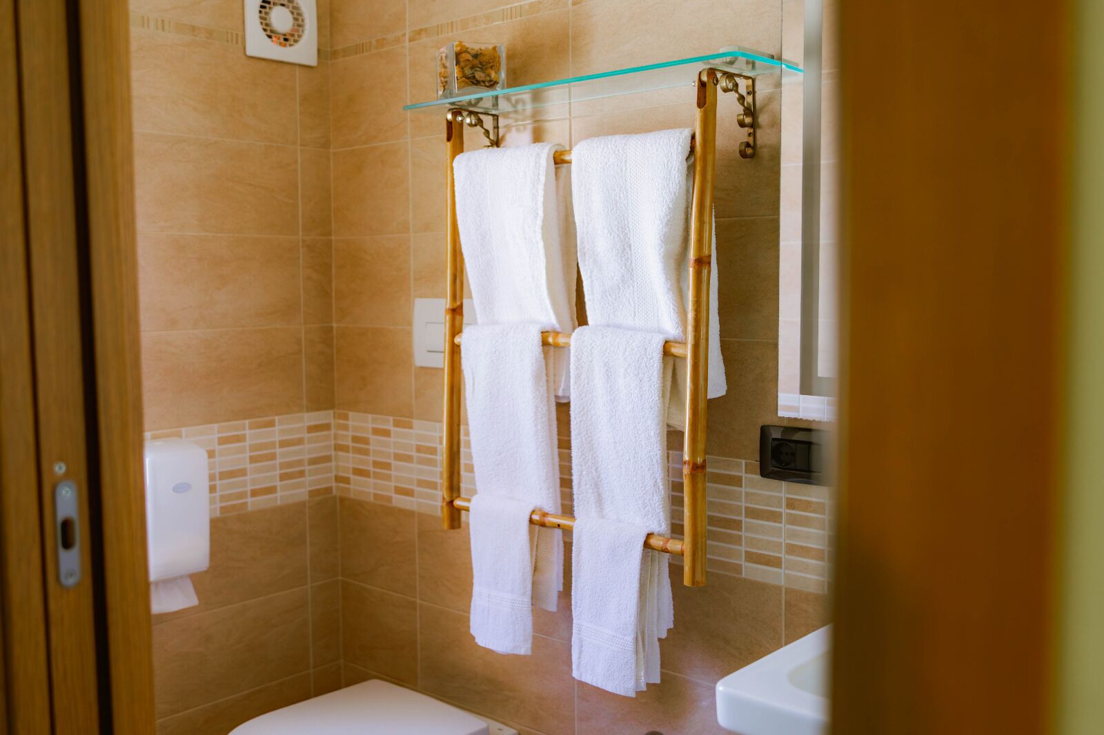 Ein Badezimmer mit einer Glastuchstange, an der mehrere weiße Handtücher hängen, einer Toilette und einer Duschkabine.