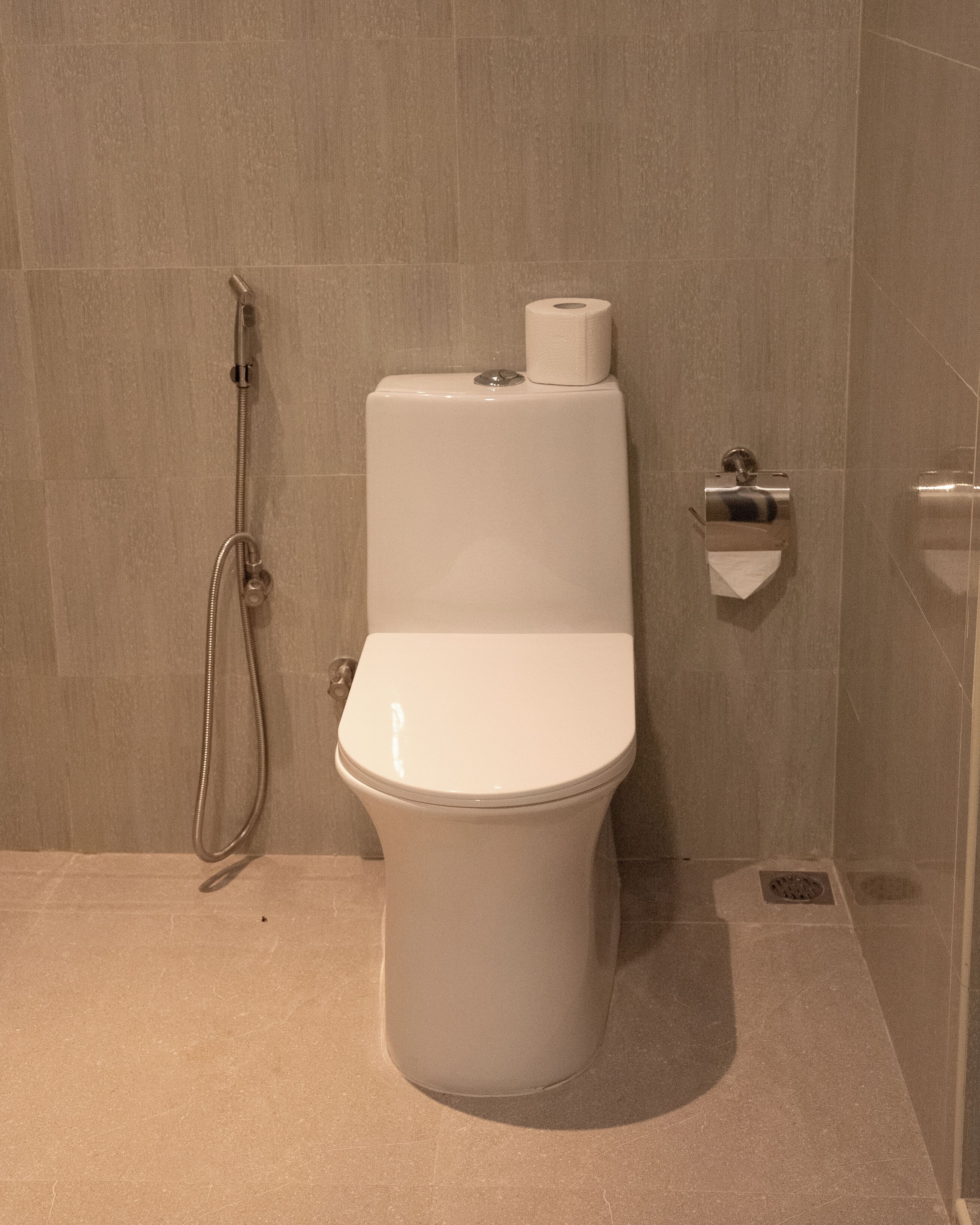 Un baño moderno con inodoro, ducha y dispensador de papel higiénico.