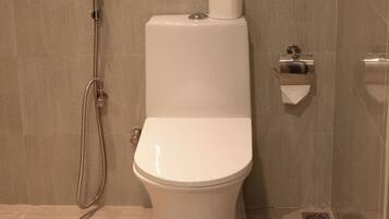 Un baño moderno con inodoro, ducha y dispensador de papel higiénico.