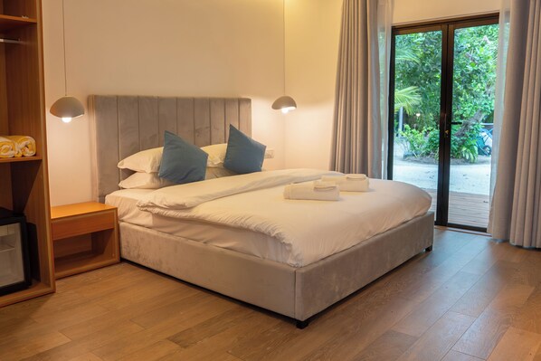 A bedroom with a bed, bedside tables, a wardrobe, and a view through a sliding door. - Arena Blanca (Rasdhoo)