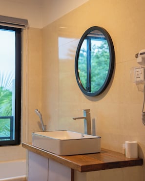 Un baño con un lavabo rectangular, un espejo y una ventana.