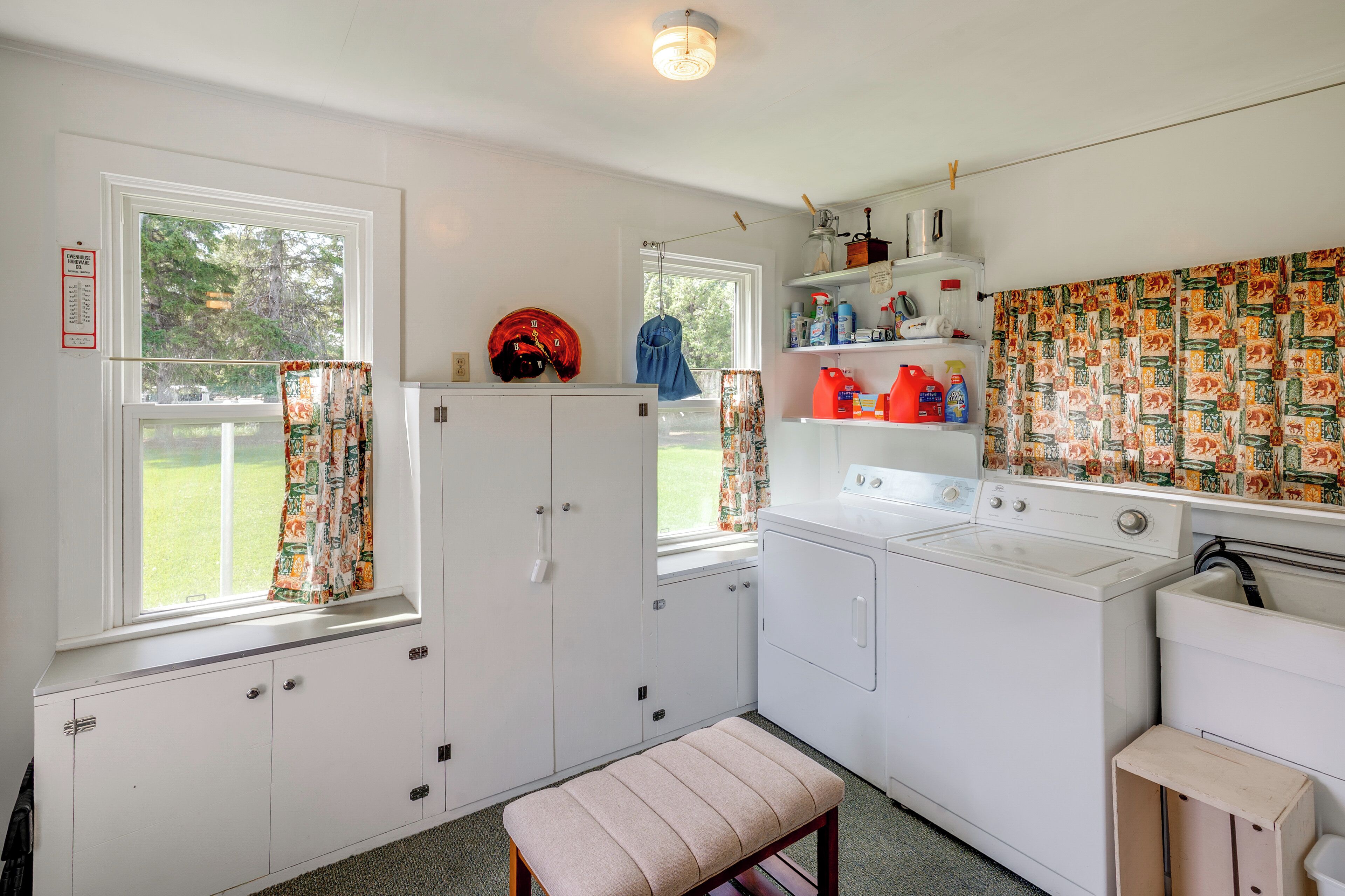 A laundry room with a washing machine, drying rack, and shelves with cleaning supplies.