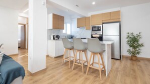 Una cocina moderna con una isla central, taburetes de bar, un refrigerador y un microondas.