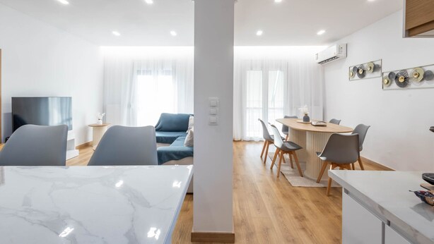 Una sala de estar moderna con una mesa de mármol, un sofá y un comedor con sillas y una mesa.