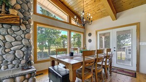 A dining area with a stone wall, wooden ceiling, and large windows. - Private Mtn-View Pool! Rogue River Valley Escape (Eagle Point)