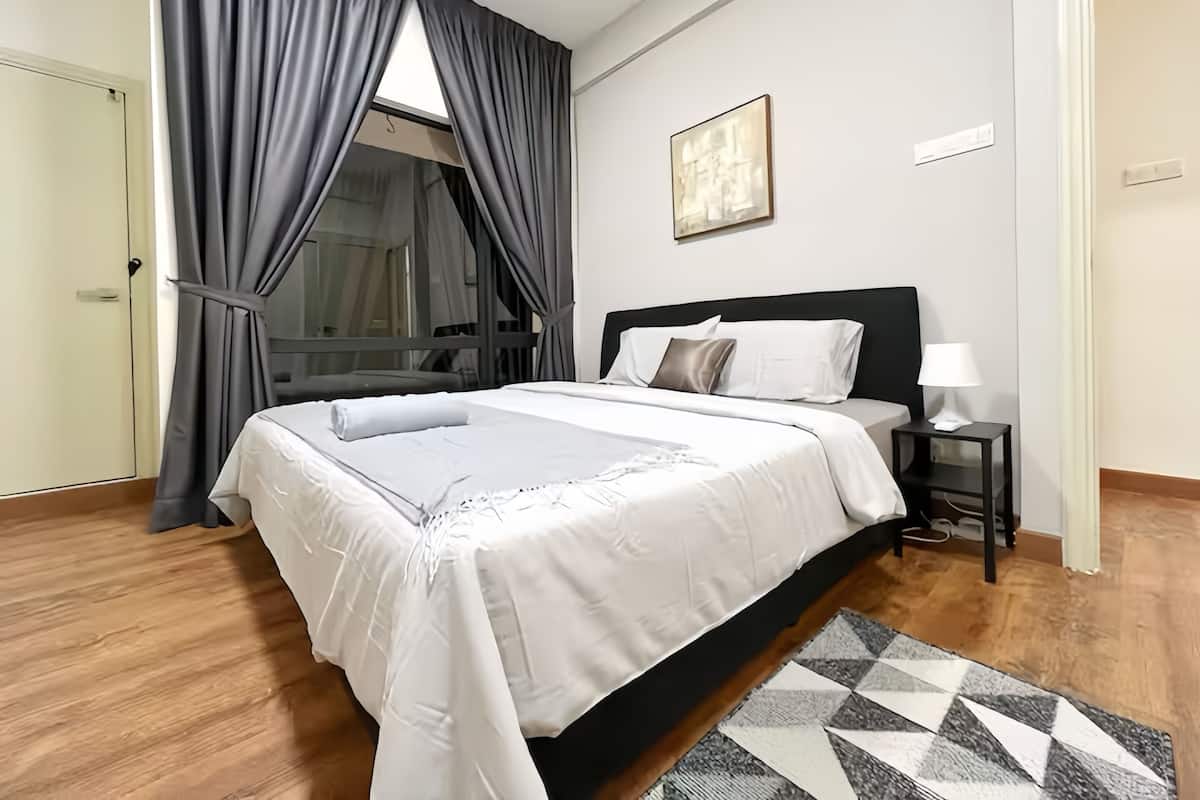 A neatly made bed with a white duvet, a black headboard, and a bedside table with a lamp.