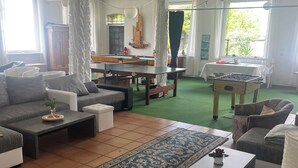Un salon comprenant un ensemble de canapés, une table basse, une table de billard et une table de baby-foot.