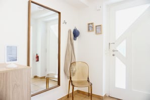 Habitación con un escritorio de madera, una silla, un espejo grande, una puerta y un extintor de incendios instalado en la pared.