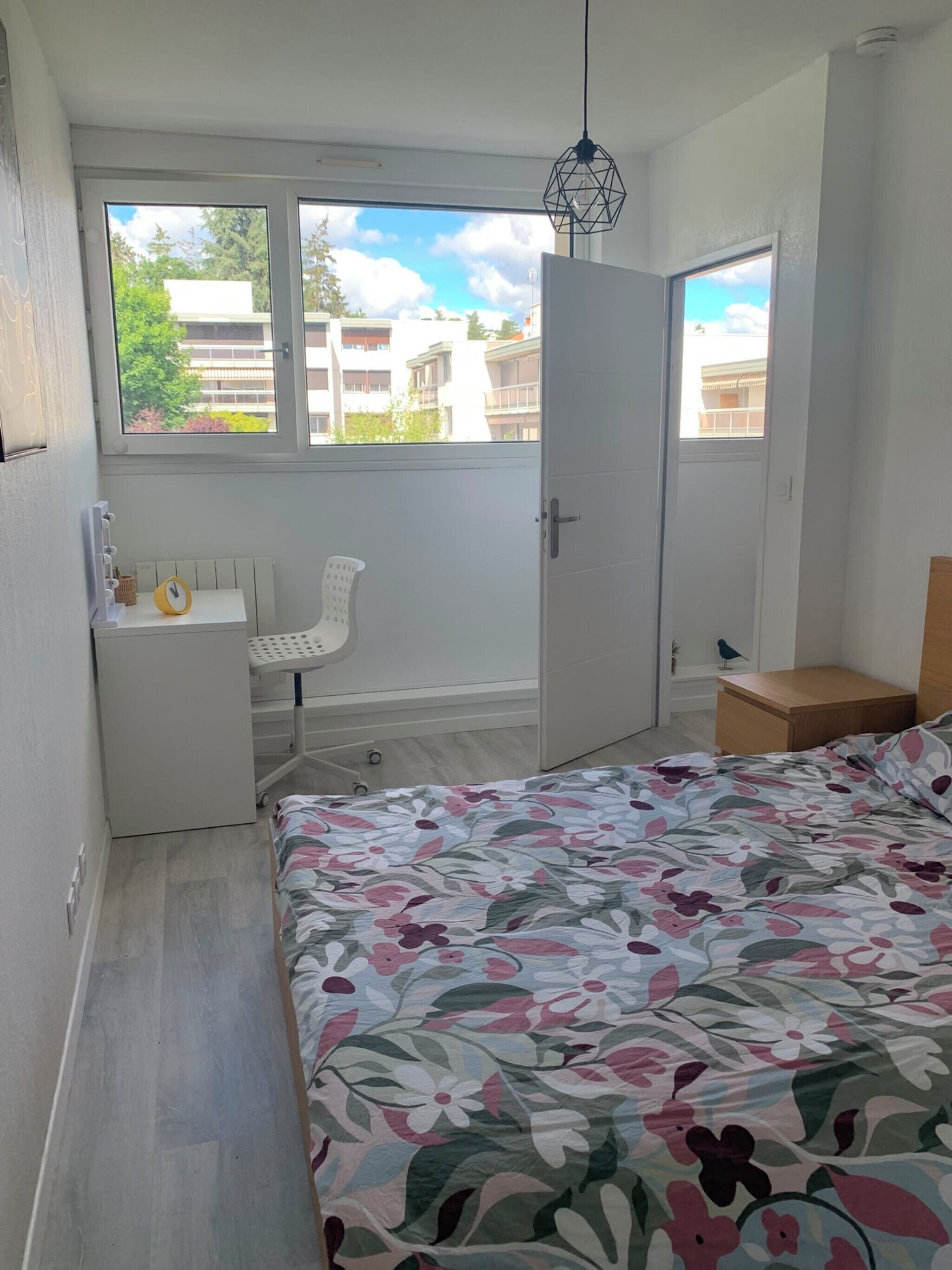 A bedroom with a bed, a desk, a chair, and a window.