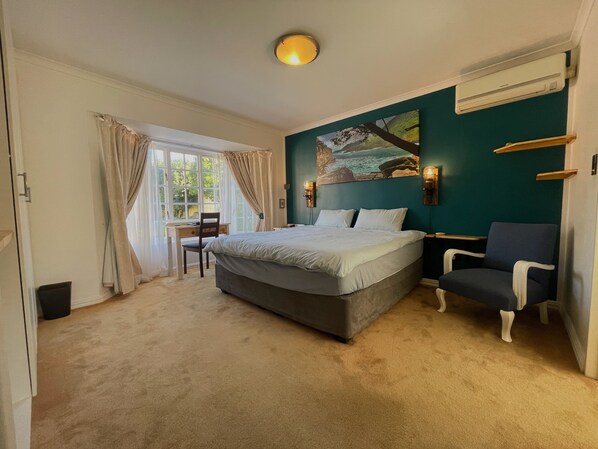 Ein Schlafzimmer mit Bett, Schreibtisch, Stuhl und einem Bild an der Wand.