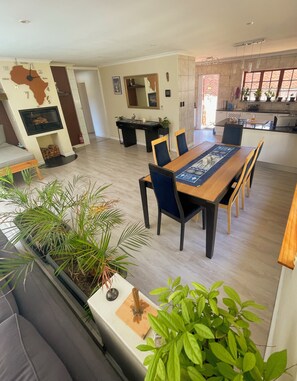 A spacious living area with a dining table, chairs, a sofa, and a fireplace. - Storms River room, 400 Mbps internet, private bathroom (Cape Town)