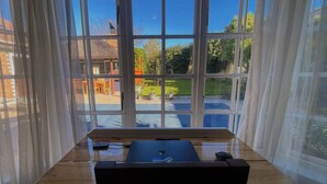 Una habitación con un ventanal grande, una mesa de madera y una computadora portátil.