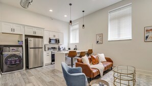 Una cocina moderna con electrodomésticos de acero inoxidable, un comedor con un sofá de cuero marrón y una sala de estar con un sillón azul.