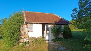A small stone house with a tiled roof, a door, and a window.