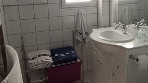A bathroom with a window, a sink, a mirror, and a towel rack.