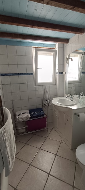 Une salle de bain avec une fenêtre, un lavabo, un miroir et un porte-serviettes.