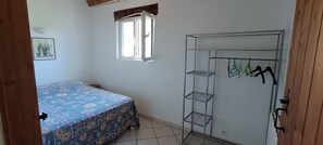 A bedroom with a bed, a wardrobe, a window, and a wall-mounted shelf. - Countryside cottage, private terrace & garden overlooking walnut & plum orchards (Penne-d'Agenais)