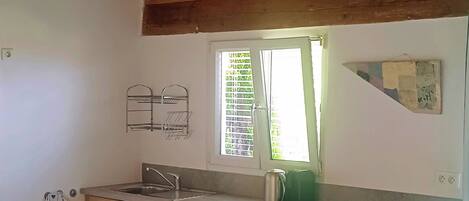 Una cocina con armarios de madera, un refrigerador blanco, un lavamanos y un comedor con sillas de metal y una mesa.