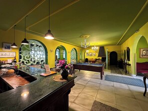 Ein Billardtisch in einem Raum mit grünen Wänden und einer Bar.