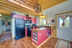 A kitchen with a central island, wooden ceiling beams, and a red and black refrigerator. - Sangre de Cristo Views! Retreat Near Wild Horses! (San Luis)