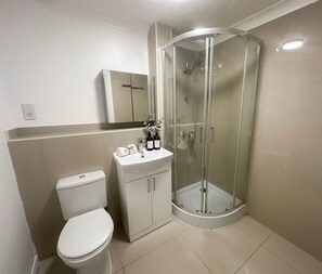 A bathroom with a toilet, a sink, and a glass-enclosed shower. - Keepers Court Luxury Stay (South Croydon)