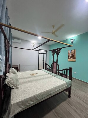 A room with a bed, a ceiling fan, a wall-mounted air conditioner, and a painting. - Azure Chameleon House (Zanzibar)