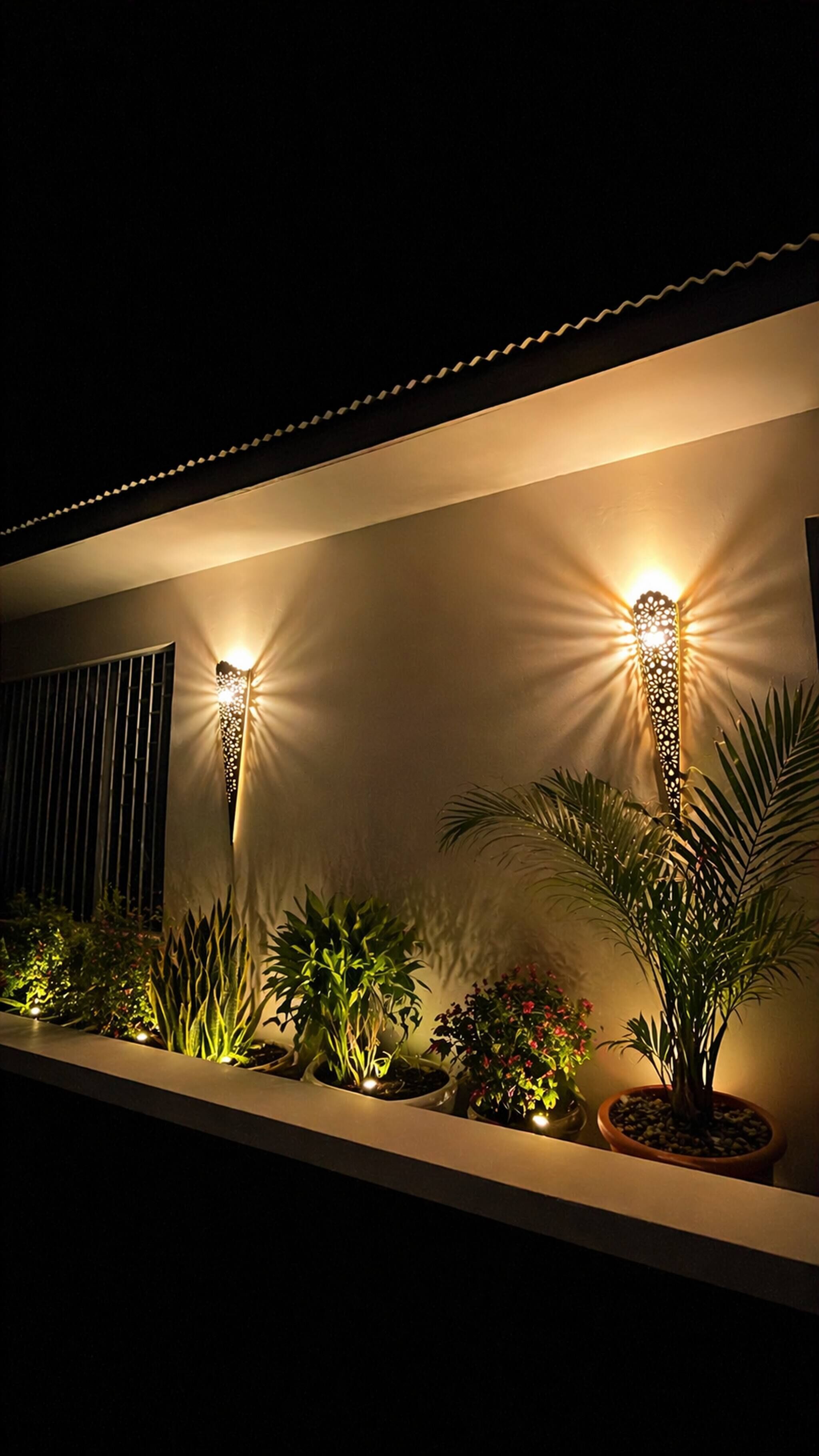 Un edificio moderno con luci decorative a parete e una fila di piante in vaso.