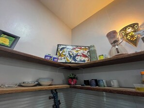 A kitchen with wooden shelves, a blender, a kettle, and various kitchenware. - Azure Chameleon House (Zanzibar)