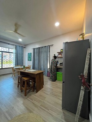 A spacious living area with a dining table, chairs, a refrigerator, and a kitchen counter. - Azure Chameleon House (Zanzibar)