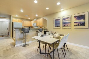 Une cuisine moderne avec des meubles en bois, un réfrigérateur blanc et un coin repas comprenant une table et des chaises.