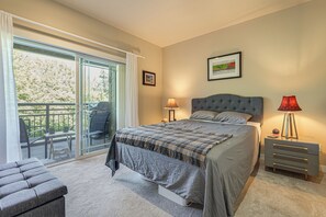 Une chambre à coucher comprenant un lit, une table de chevet, une lampe, un tableau encadré et un balcon avec des chaises.
