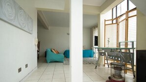 A room with a tiled floor, a sofa, a table, and a heater.