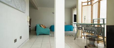 A room with a tiled floor, a sofa, a table, and a heater.