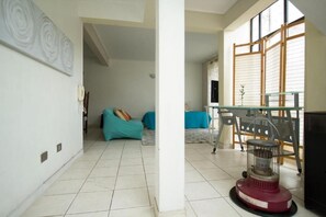 Une pièce avec un sol carrelé, un canapé, une table et un radiateur.