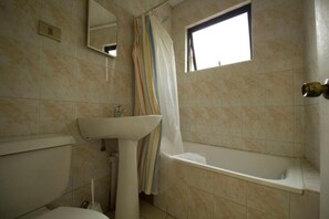 Une salle de bain comprenant des toilettes, un lavabo, une baignoire et une fenêtre.