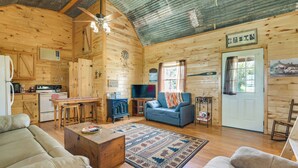 Interior de una cabaña de madera con cocina, sala de estar y una mesa de comedor.