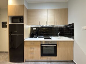 A modern kitchen with wooden cabinets, a built-in microwave, a coffee maker, and a stainless steel sink. - SmartLiving Central Apt 11 (Thessaloniki)
