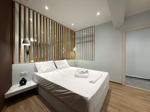 Une chambre d’hôtel moderne avec un grand lit, des lampes de chevet, une table de chevet et un miroir.
