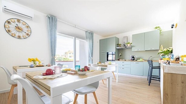 Una cucina moderna con zona pranzo, un orologio al muro e vista sull'esterno.
