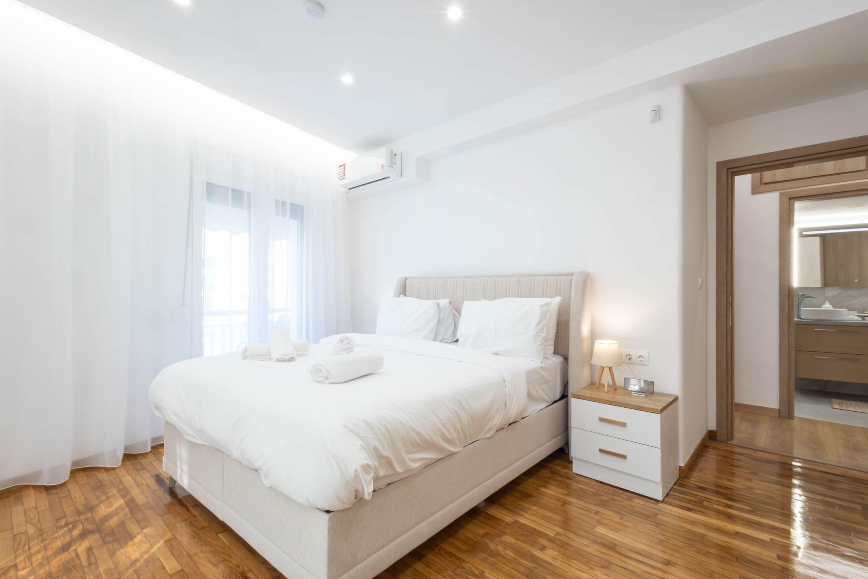 Une chambre à coucher moderne avec un grand lit, une table de chevet avec une lampe et un plancher en bois.