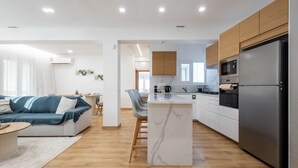Una cocina moderna con una isla central, electrodomésticos integrados y un comedor.