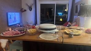 Una mesa de comedor con diferentes alimentos y una pantalla de televisión mostrando un programa.