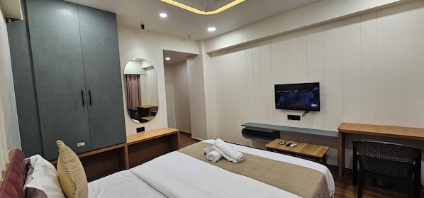 A hotel room with a bed, a desk, a TV, a wardrobe, and a mirror.