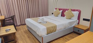A hotel room with a bed, a desk, a chair, and a nightstand.