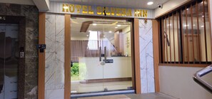 L’entrée de l’hôtel Silvera Inn, avec un comptoir de réception, un bouton pour appeler le voiturier et un panneau indiquant l’emplacement de la réception.