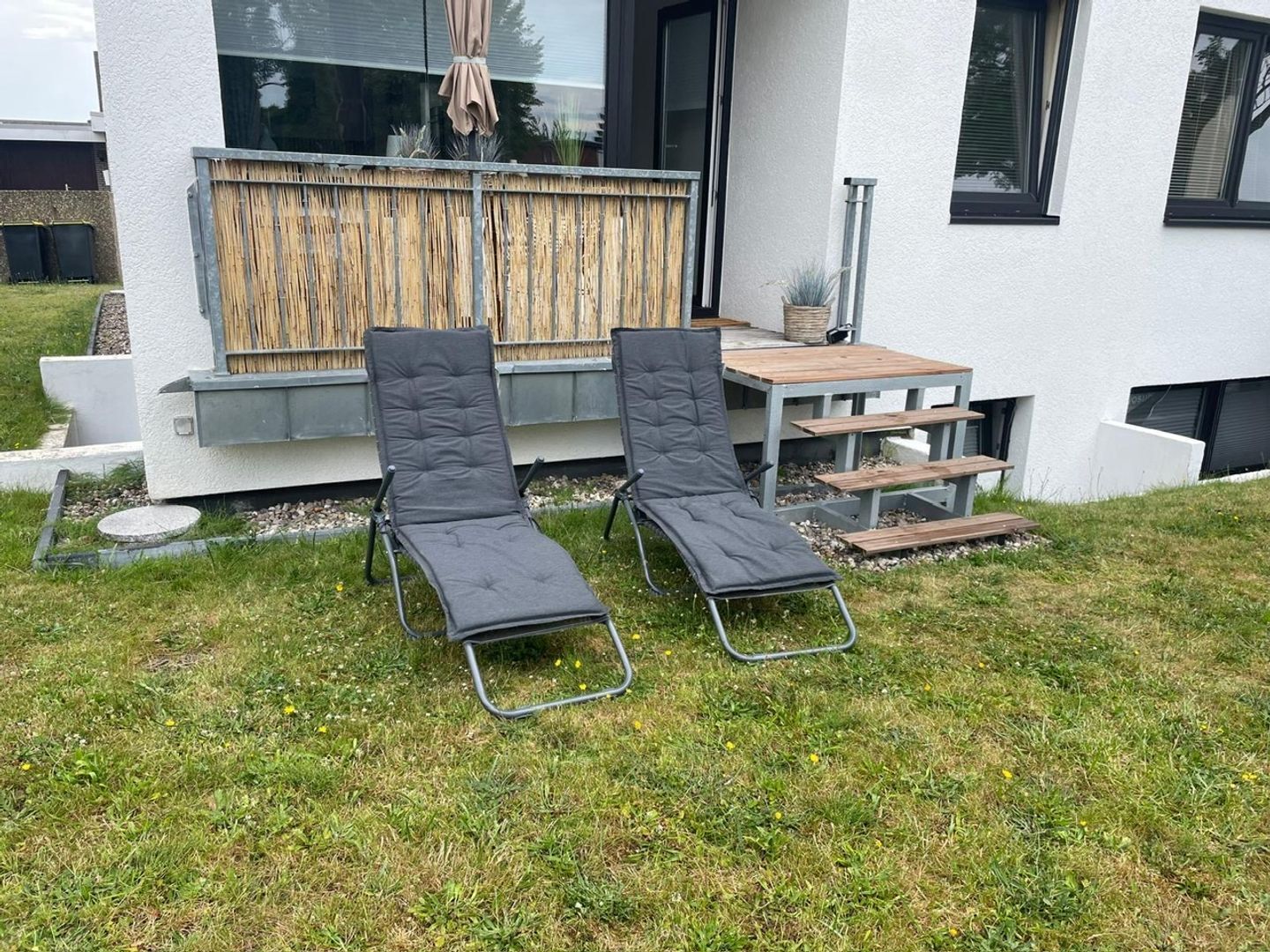 Zwei schwarze Lounge-Stühle mit einem Holztisch und Treppen, die zu einem Fenster führen.
