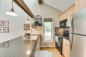 A modern kitchen with granite countertops, stainless steel appliances, wooden cabinets, and a window with a view. - Only 8/22-8/29 Still Available for Summer 2026! (Harbor Springs)