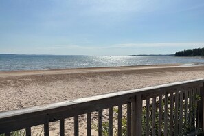 A beach with a wooden deck in the foreground. - Only 8/22-8/29 Still Available for Summer 2026! (Harbor Springs)